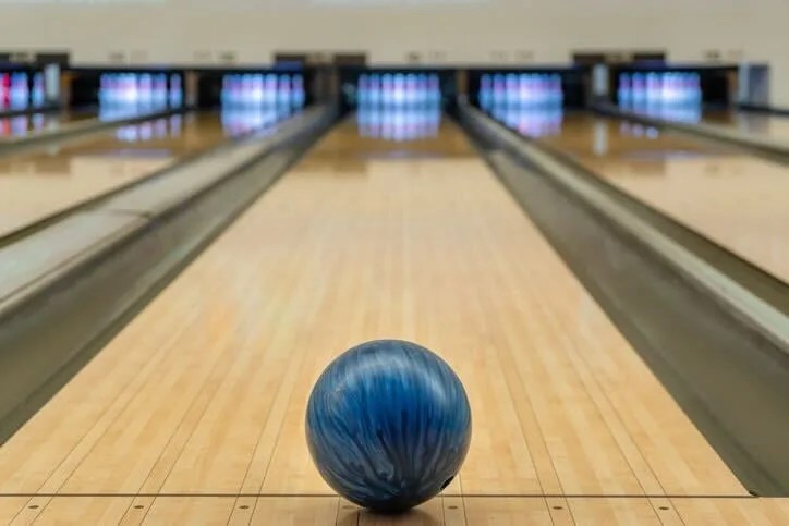 A blue bowling ball sits on a bowling lane.