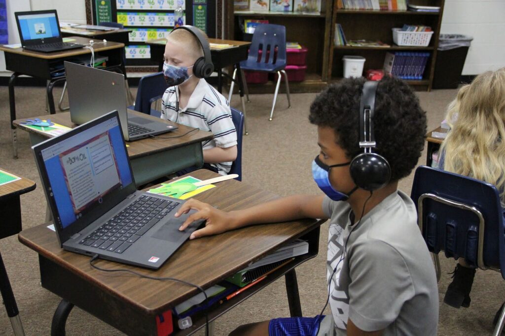 Children in masks learning in a classroom.