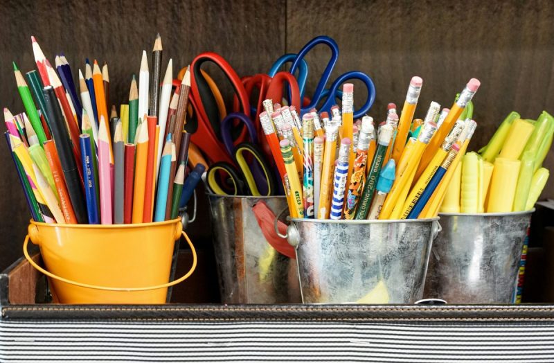 Assorted school supplies held in various metal cups.