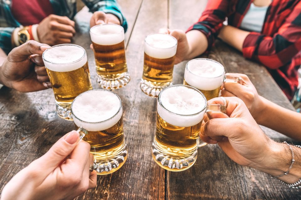People holding full mugs of lager.