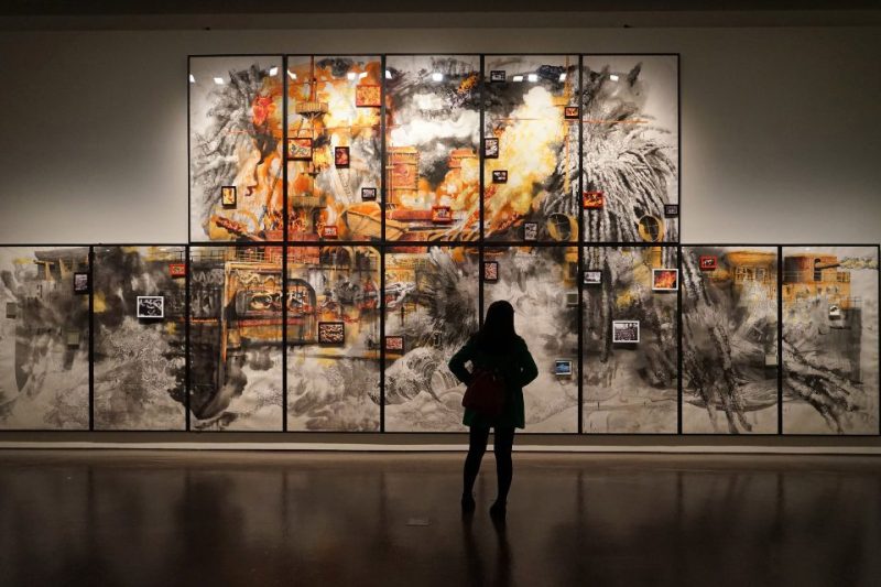 A woman looking at a wall art exhibit in a museum