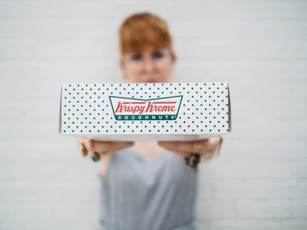 Woman holding Krispy Kreme box.