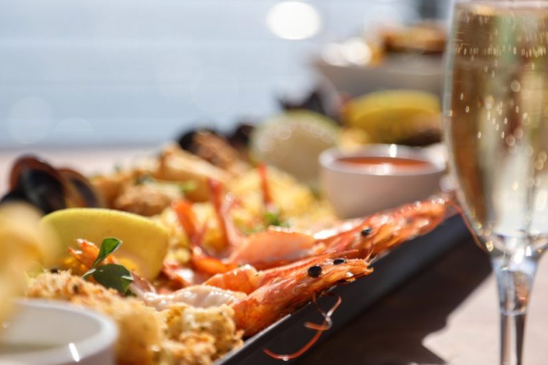 A tray of seafood and a glass of sparking wine at a seaside restaurant.