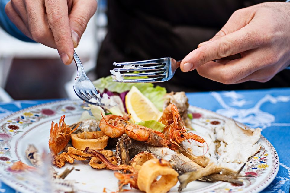 A person eating a plate of seafood.