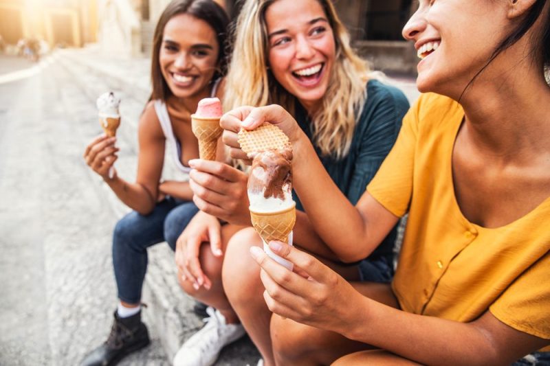 Three women laugh and eat ice cream cones