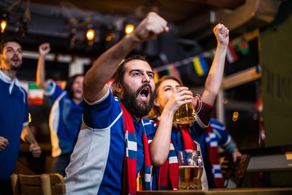 A group of guys watching professional soccer at a pub.
