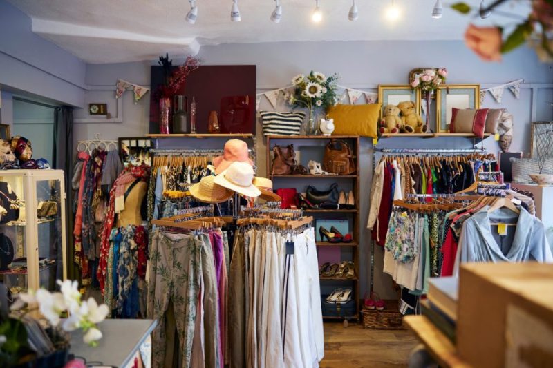 The inside of a thrift store with lots of clothes and hats.