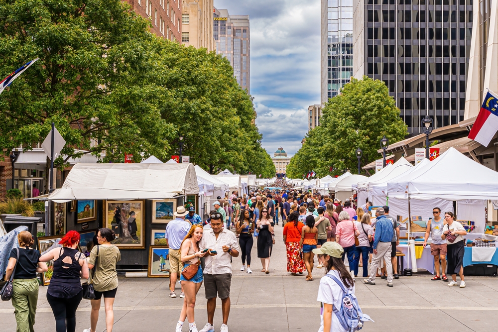 A scatter of people walking around on a Raleigh street for a festival