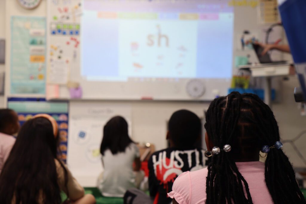 First grade class facing the front of classroom to learn.