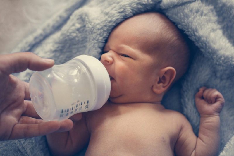 Newborn baby drinking milk from a bottle.
