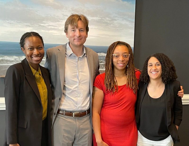 Group of 4 poses for a portrait.