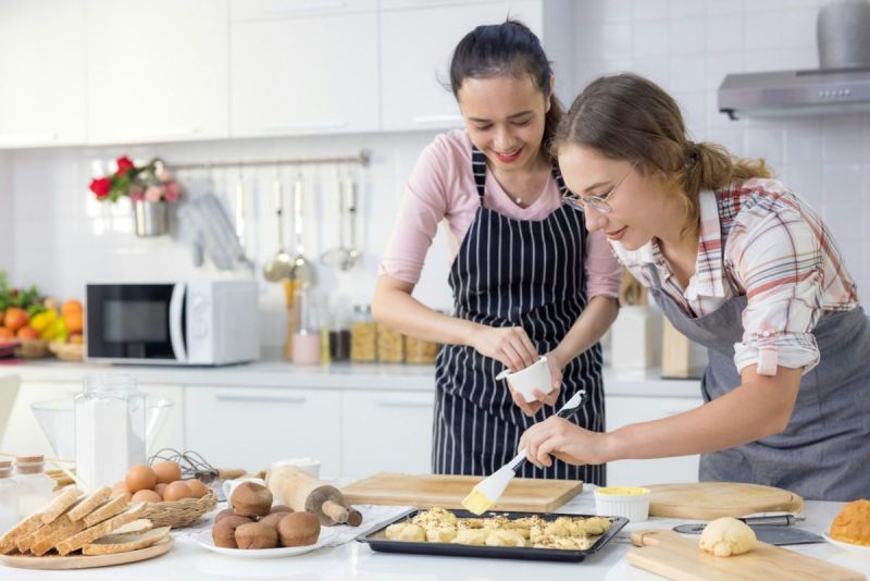 Two women wearing aprons preparing a holiday meal.