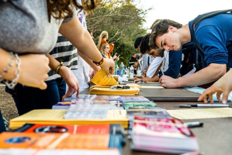 Students gather around a table covered in voting information