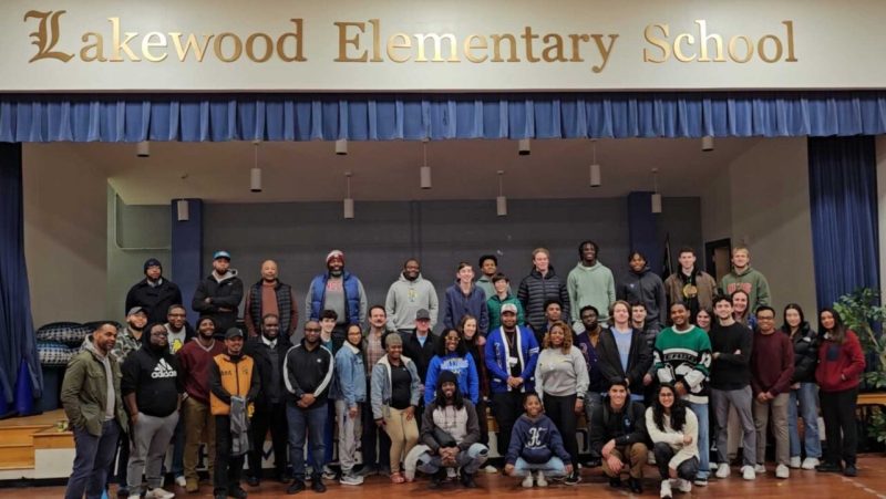 Local Durham teacher and dozens of volunteers pose for group photo at a elementary school.