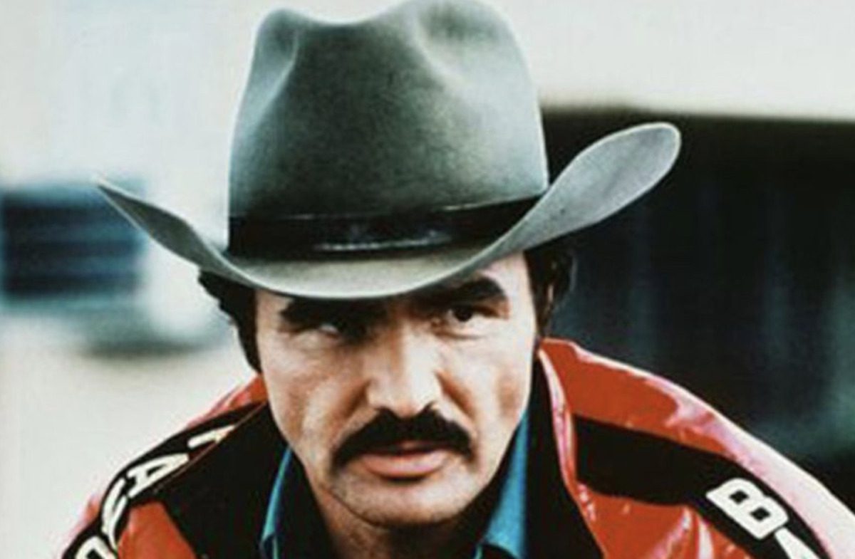 Burt Reynolds in hat and red jacket