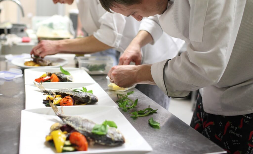 chefs in a line plate food with their hands