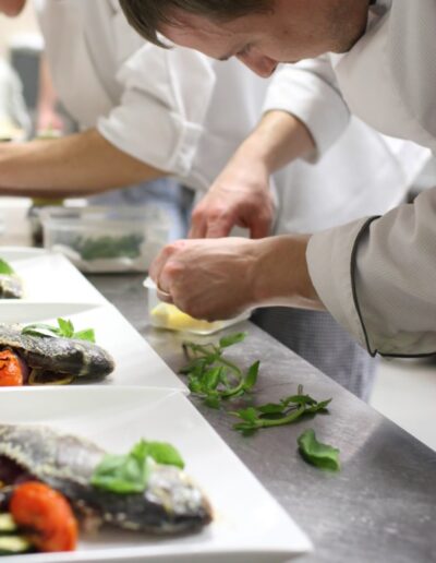 chefs in a line plate food with their hands