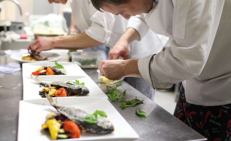 chefs in a line plate food with their hands