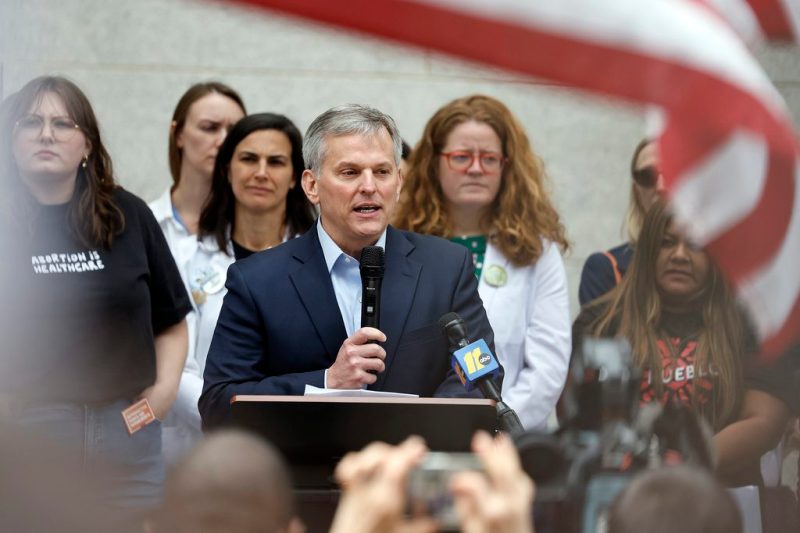 NC Governor Josh Stein speaks at a podium in front of repro rights advocates.