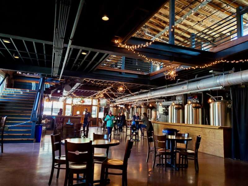 the interior of a bar with seats, tables, lights, and people