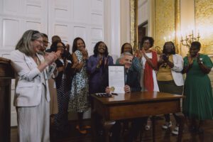 Photo of Gov. Josh Stein posing with the signed proclamation recognizing April 11-17 as Black Maternal Health Week. Behind him stand several advocates including NC Senator Natalie Murdock.